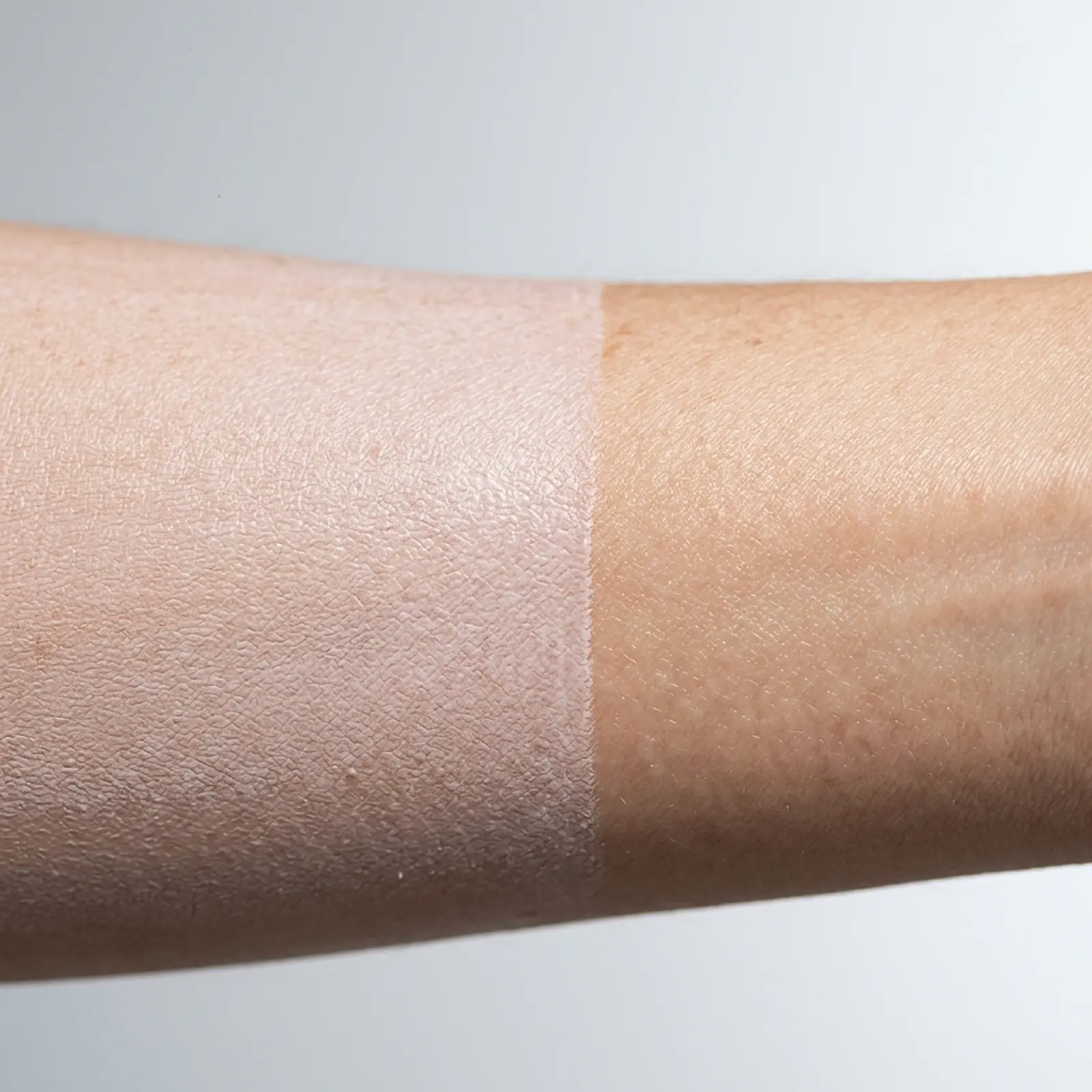 Macro shot of sunscreen on skin, coated versus uncoated skin on the arm.