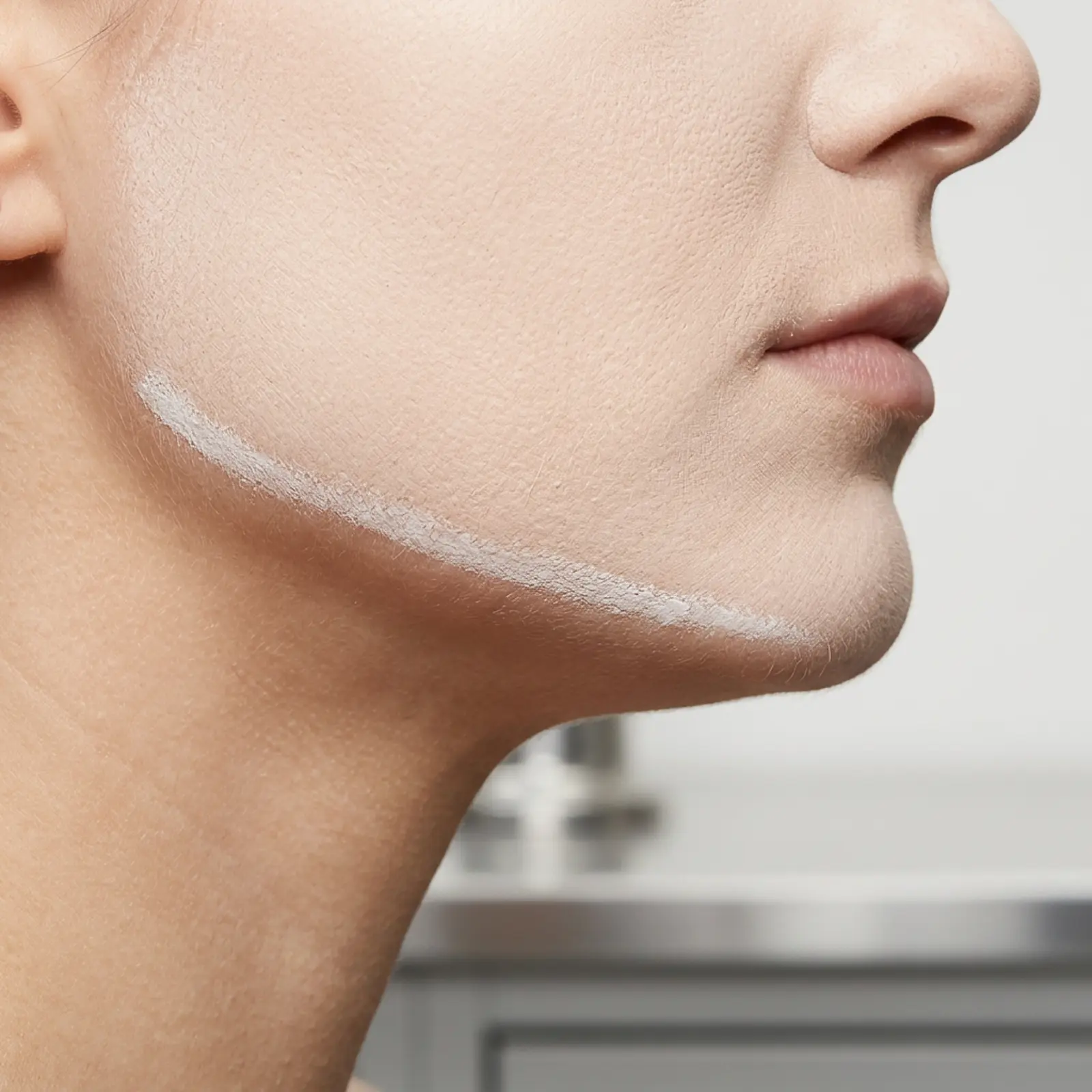 Close-up of jawline and neck showing a visible mineral residue line at the jaw boundary, studio photograph