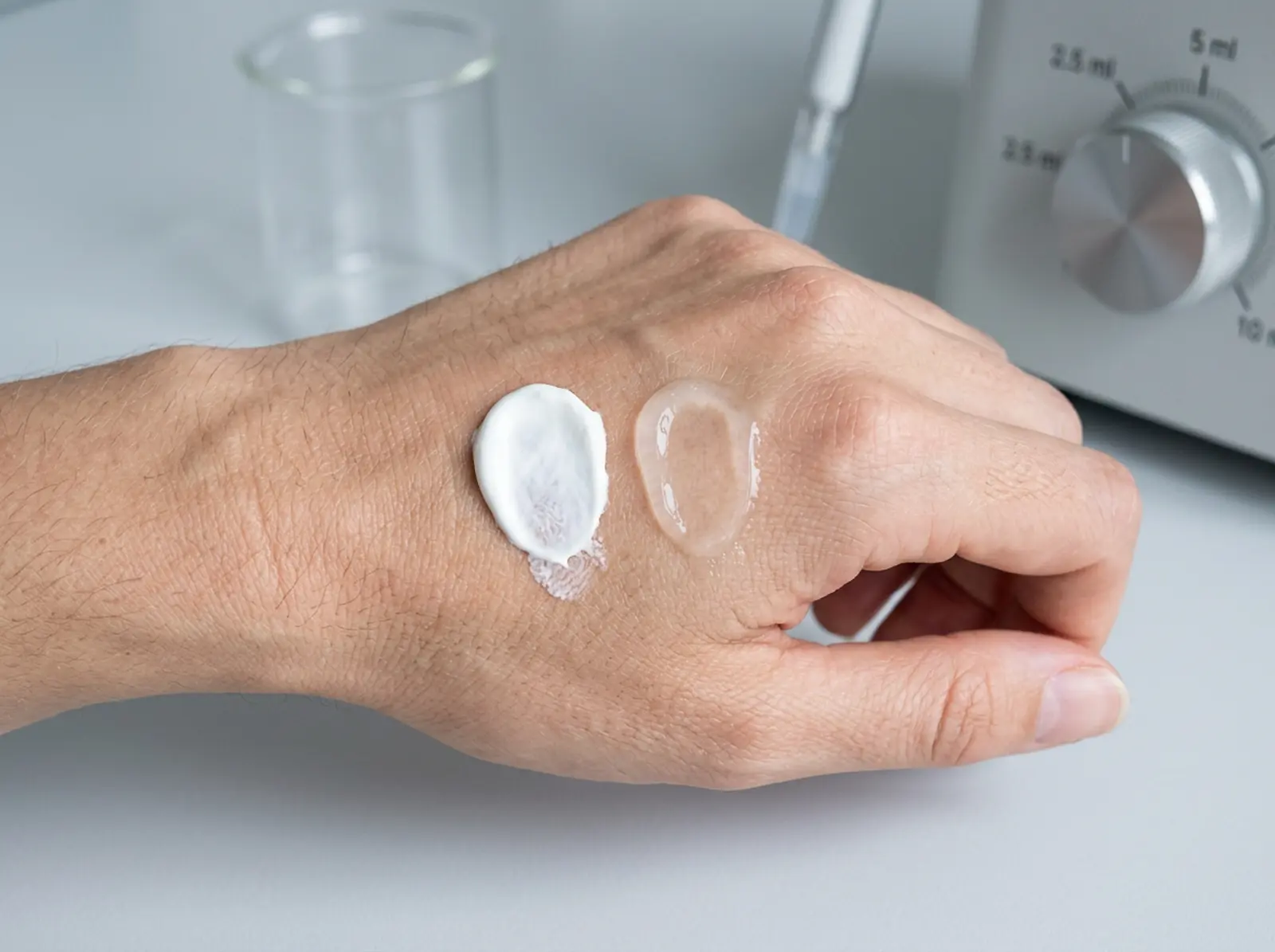 Macro shot: two sunscreens on the back of a hand, comparing finish and coverage.