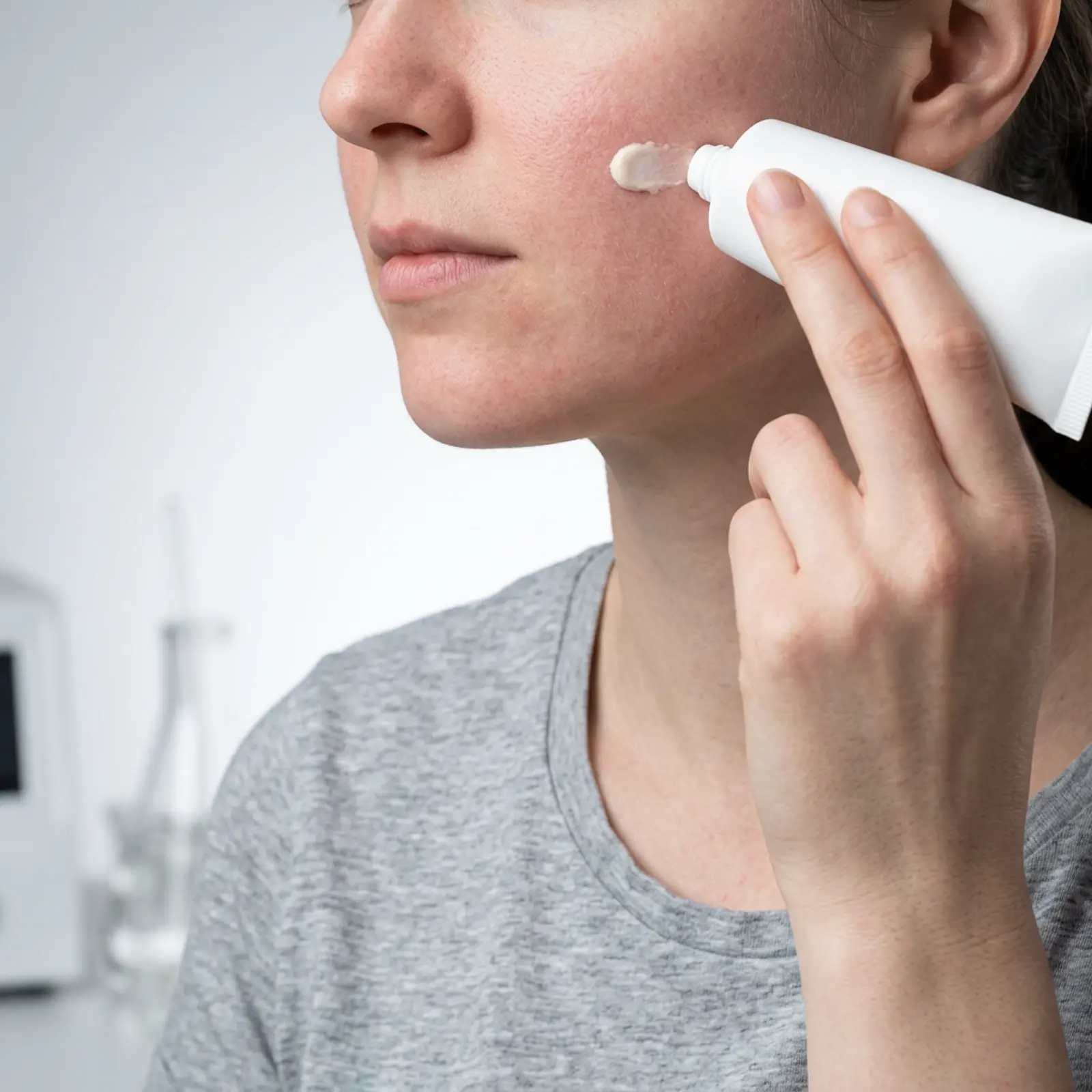 Macro shot: sunscreen application in the studio, cool lighting, neutral background.